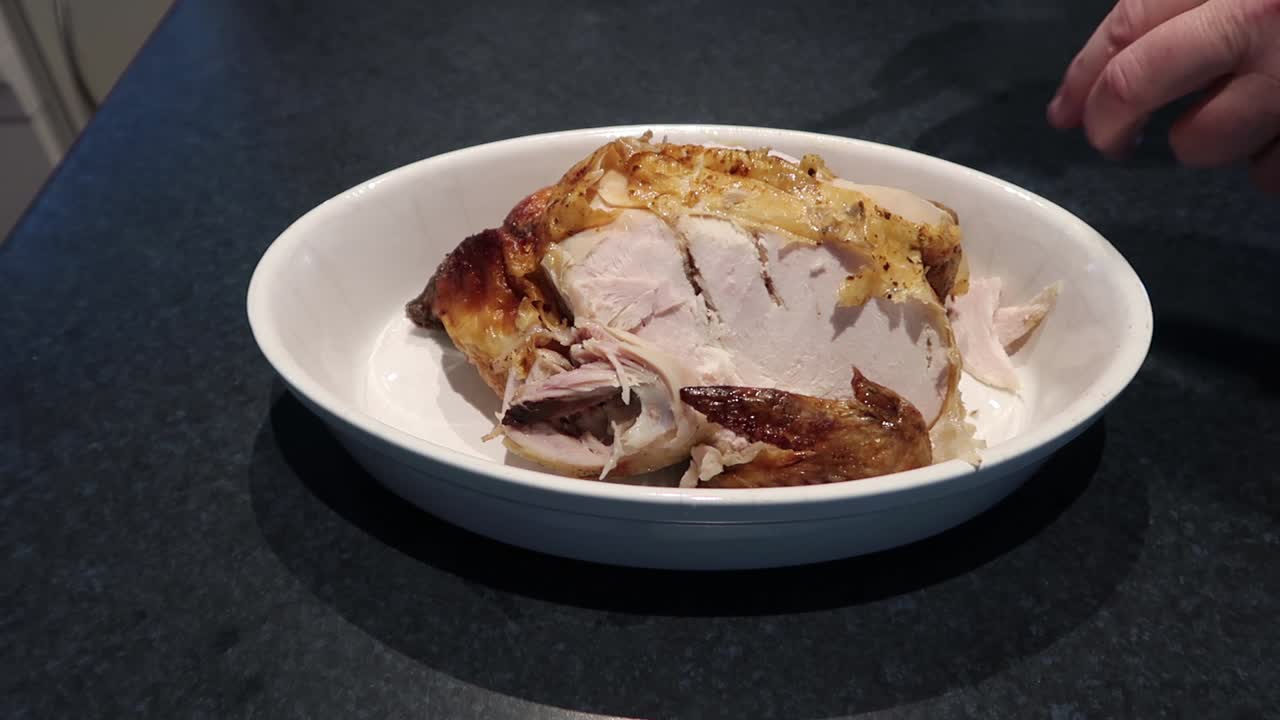 Man cutting or carving a hot roast chicken