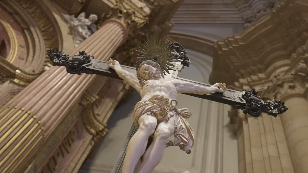Escultura ornamentada de un crucifijo en ángulo bajo iluminada por la luz sagrada de una iglesia