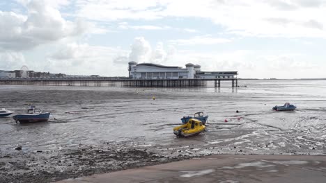 last section of the grand pier weston-super-mare with a cloudy and blue sky in the background, small boats moored in the sand banks