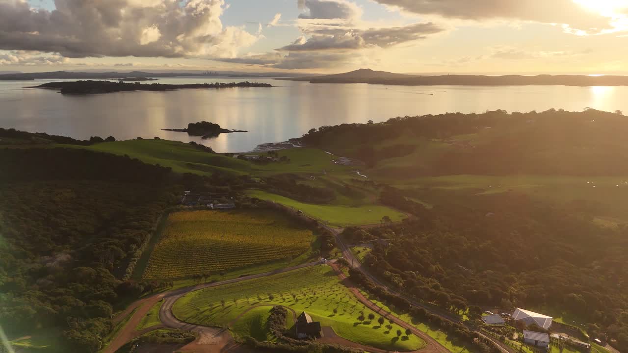 Golden hour in New Zealand with reflection on water river. Growing fields and vineyards on island of Waiheke Island,NZ Aerial top down.