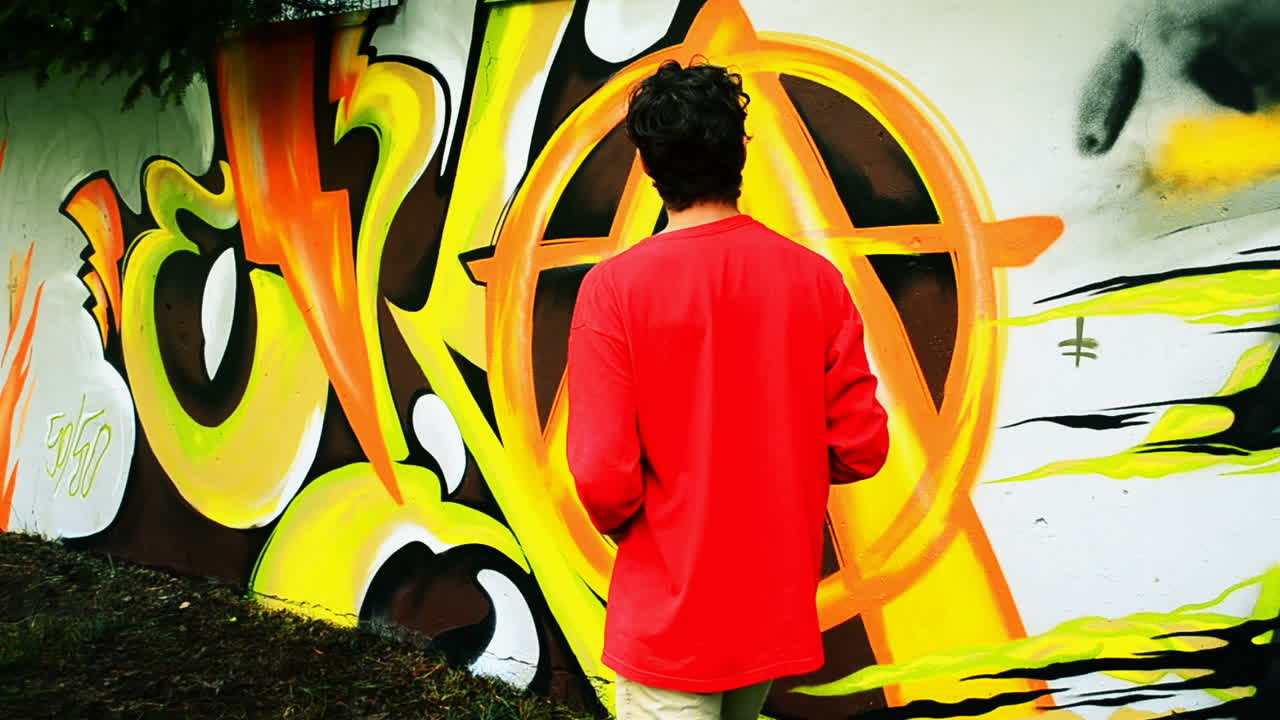 L'artista realizza graffiti su una recinzione. Disegno astratto