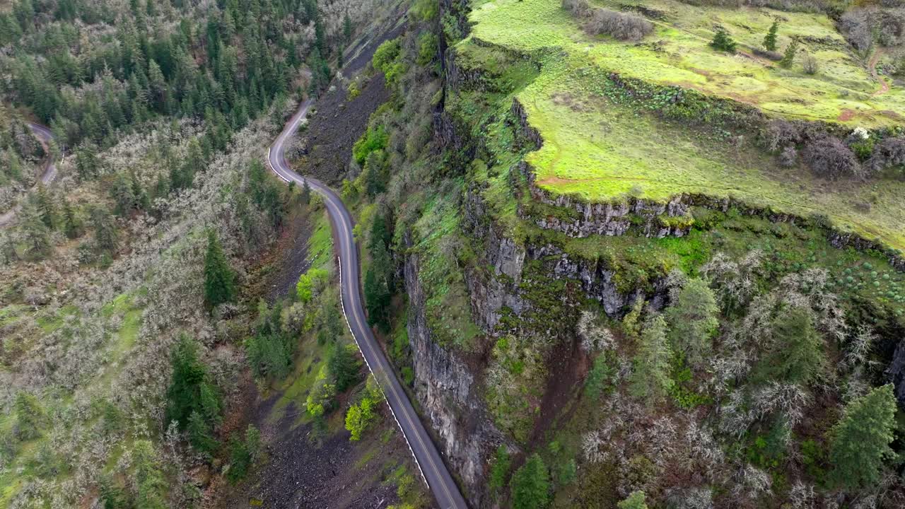 Panoramica aerea con drone DJI che nasconde una strada ventosa dietro un'alta scogliera vicino al punto panoramico Rowena Crest nell'area panoramica nazionale del Columbia River Gorge a Mosier, Oregon, prima dell'incendio