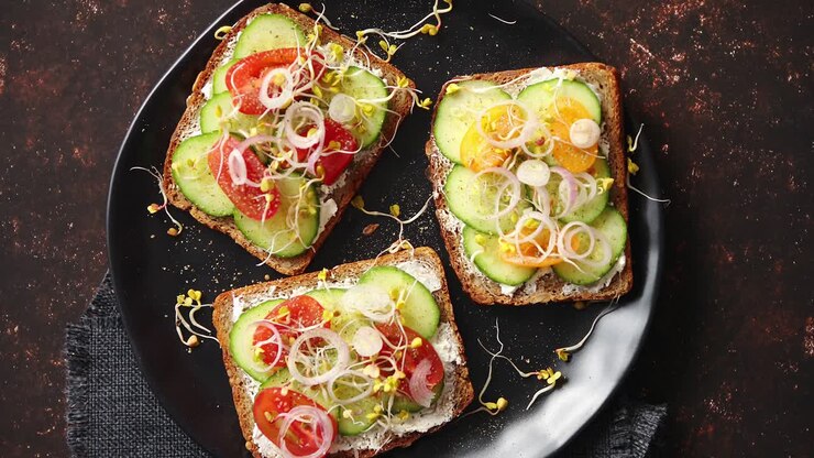 Healthy toasts with cucomber tomatoes and crumbled feta and radish sprouts