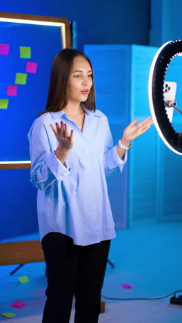 beautiful brunette girl speaks to camera with light ring. happy positive lady talks and claps her hands. vertical video.