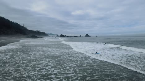 Vista-Aérea-Volando-Sobre-Surfistas-En-El-Agua-Fría-En-Indian-Beach-En-Oregon