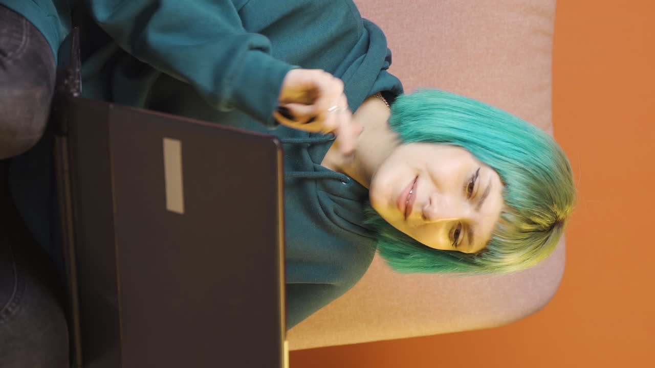 노트북에서 보는 것에 만족한 수직 비디오, 젊은 여성은 고개를 끄덕인다.