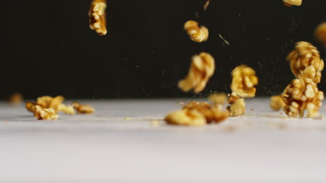 close up shot of walnuts dropping onto marble surface against black studio background shot in slow motion