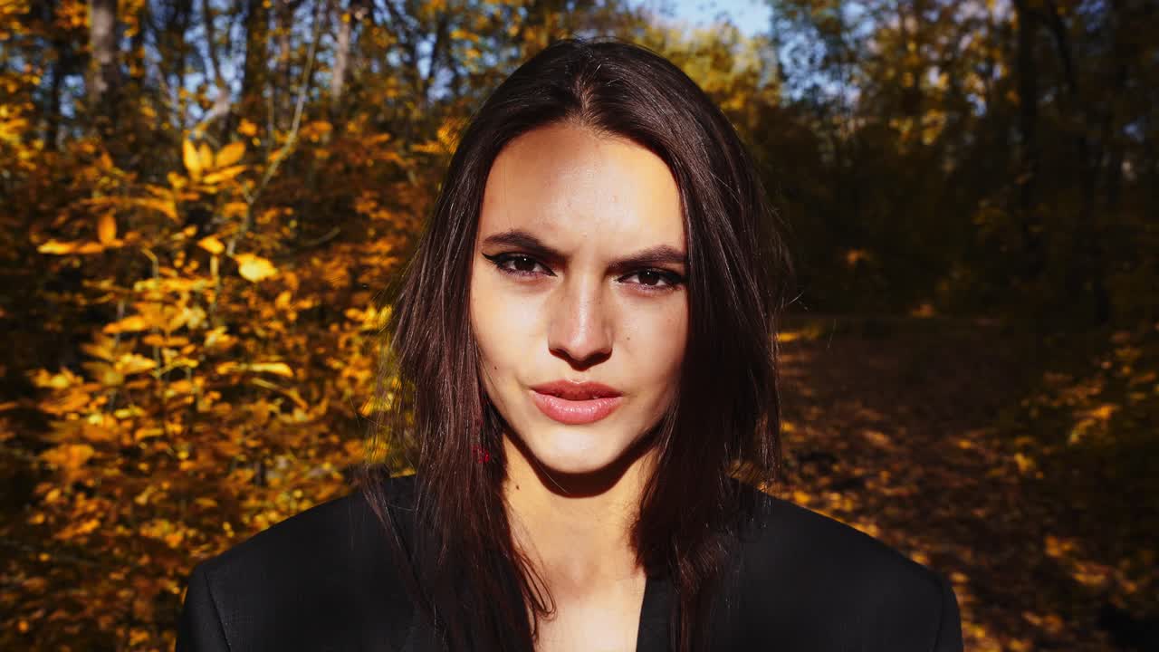 A Captivating Portrait of a Young Woman in Autumn Surroundings, Highlighting Her Strong Expression Amidst a Background of Golden Leaves and Nature's Beauty