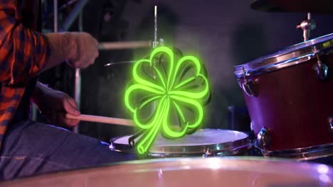 animation of st patrick's day green shamrock neon over drummer on stage