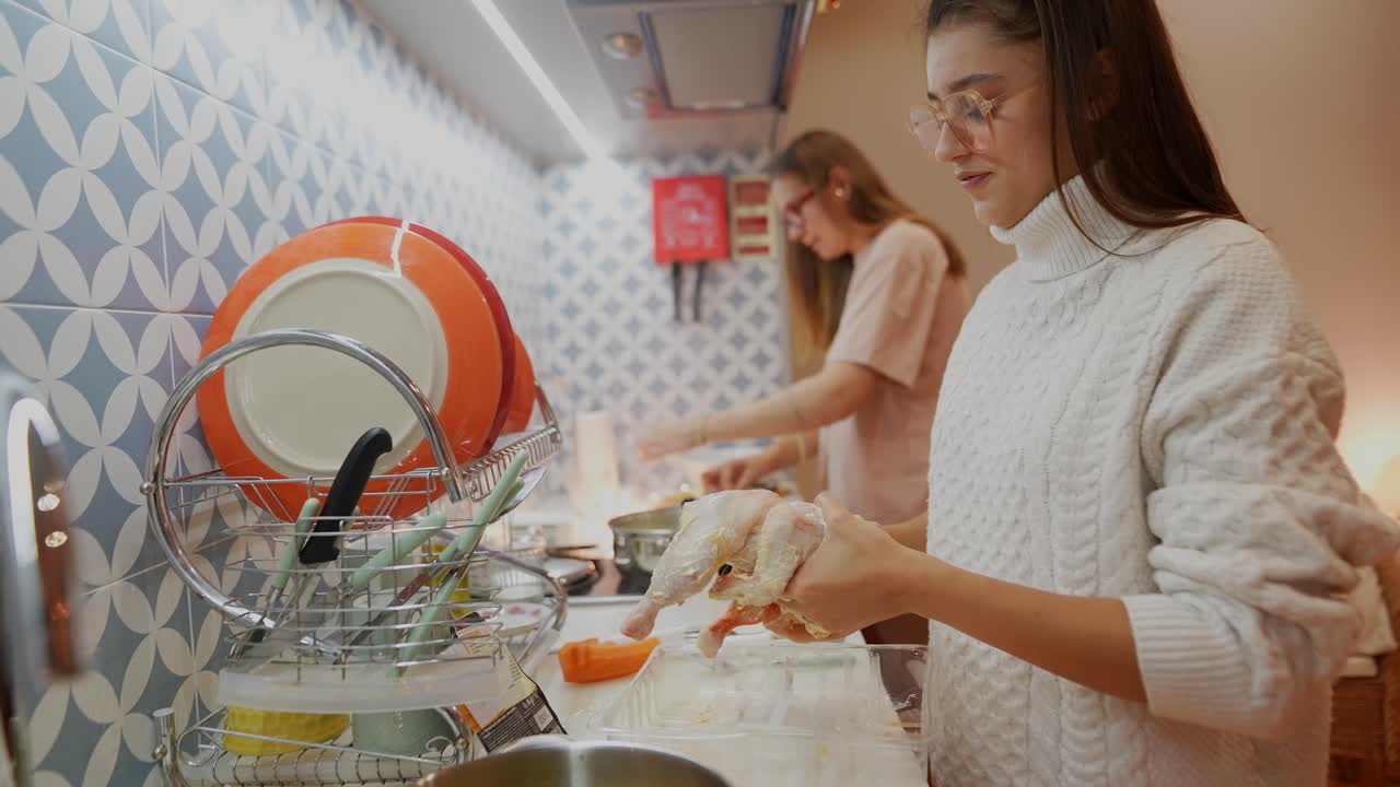 mujeres jóvenes cocinando pollo en la cocina