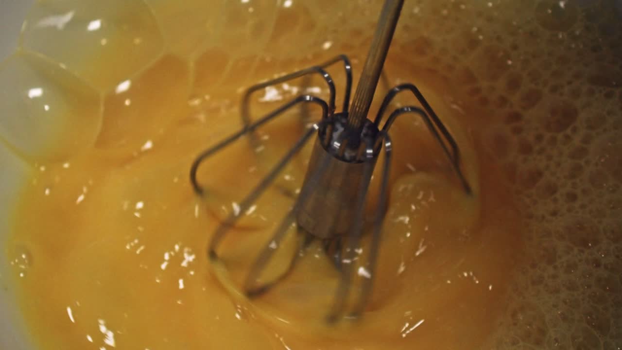 맛있는 오믈렛을 만들기 위해 저어 스틱으로 계란을 때리는 - 클로즈업