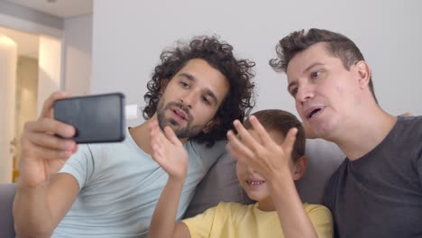 padres homosexuales positivos y niño usando celular para llamadas de video