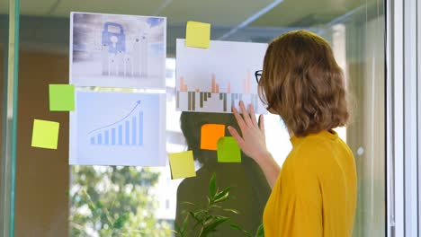 Rear-view-of-businesswoman-looking-at-graphs-in-modern-office-4k