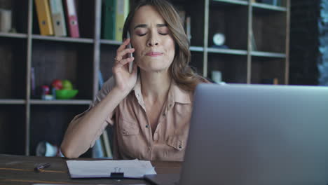 Frustrated-woman-talking-on-mobile-phone.-Business-lady-working-in-office