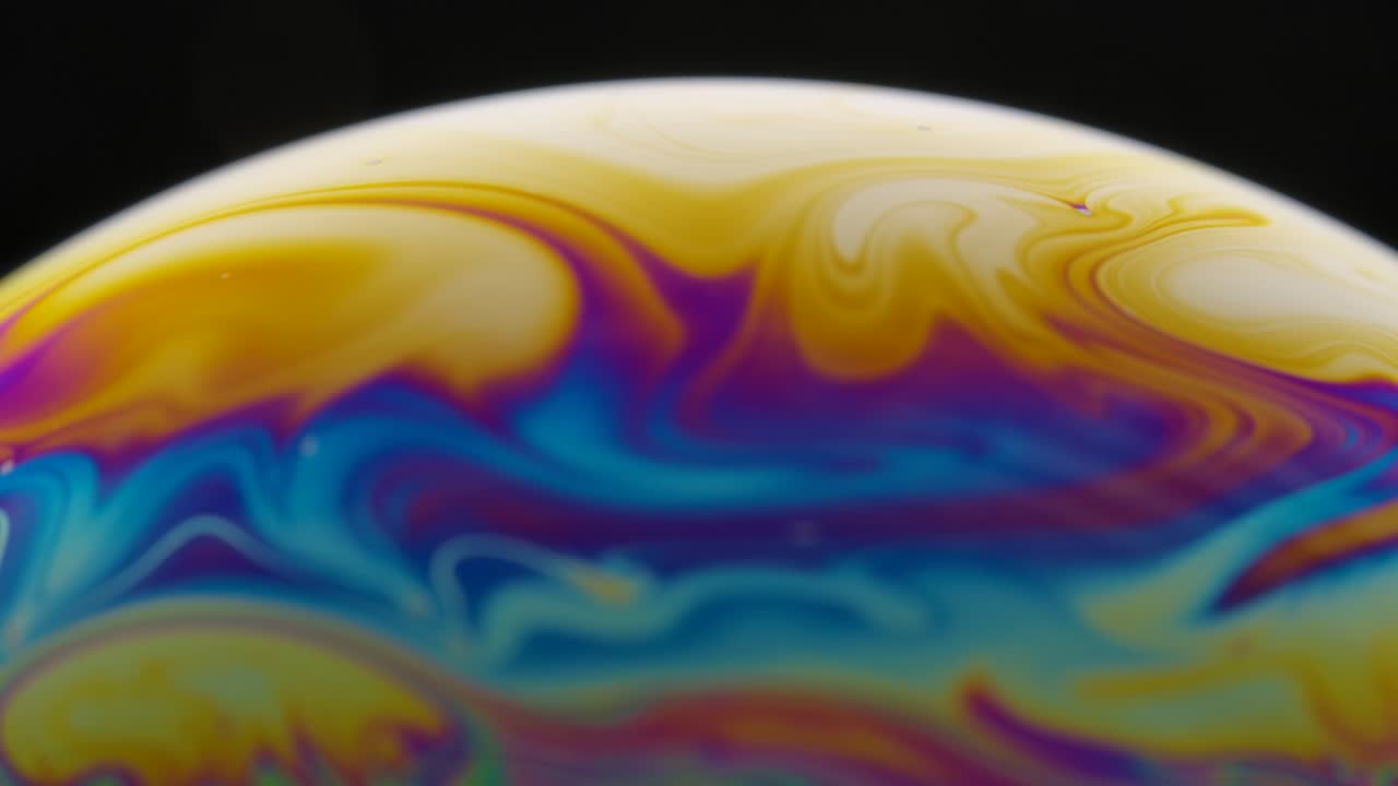 una toma macro de la superficie de una película delgada de jabón con colores de arco iris que crea un hermoso efecto de remolino. semicírculo de una burbuja de sabón con rayas de colores en un fondo negro. primer plano. cámara lenta