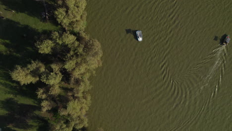 families using pedal boats, and next to them people are having a picnic on the banks of the lake of the yarkon park tel aviv, the park includes big lawns, sports facilities and botanical gardens