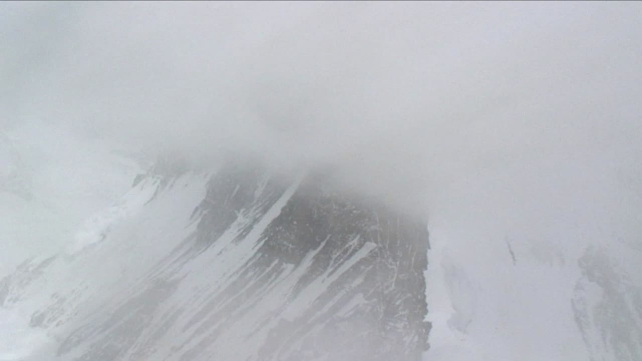 눈과 안개를 뚫고 등반하는 산악인