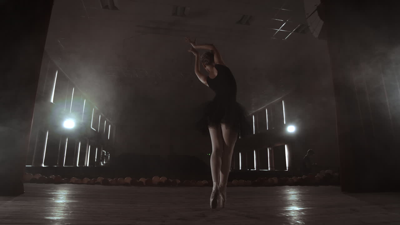 movimiento lento: prima ballet en un vestido negro realiza rotaciones y baila movimientos graciosos ensayando un programa en solitario. la cámara se mueve en gimbal.