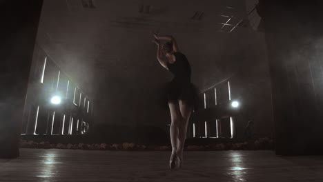 slow motion: prima ballet in a black dress performs rotations and dance graceful movements rehearsing a solo program. the camera moves on gimbal.