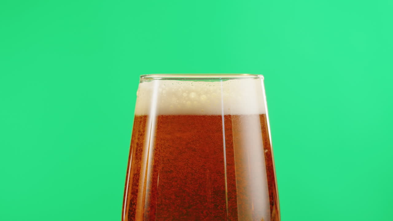 un vaso de cerveza sobre un fondo verde
