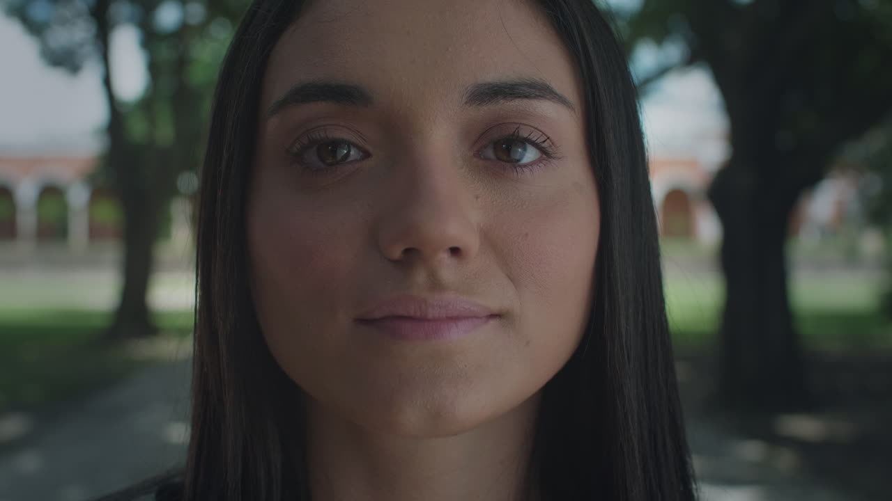 High-quality 4K shot of a young brunette in natural light, slowly opening her eyes in a park setting. She has a peaceful, daydreaming expression. Ideal for nature, mindfulness,