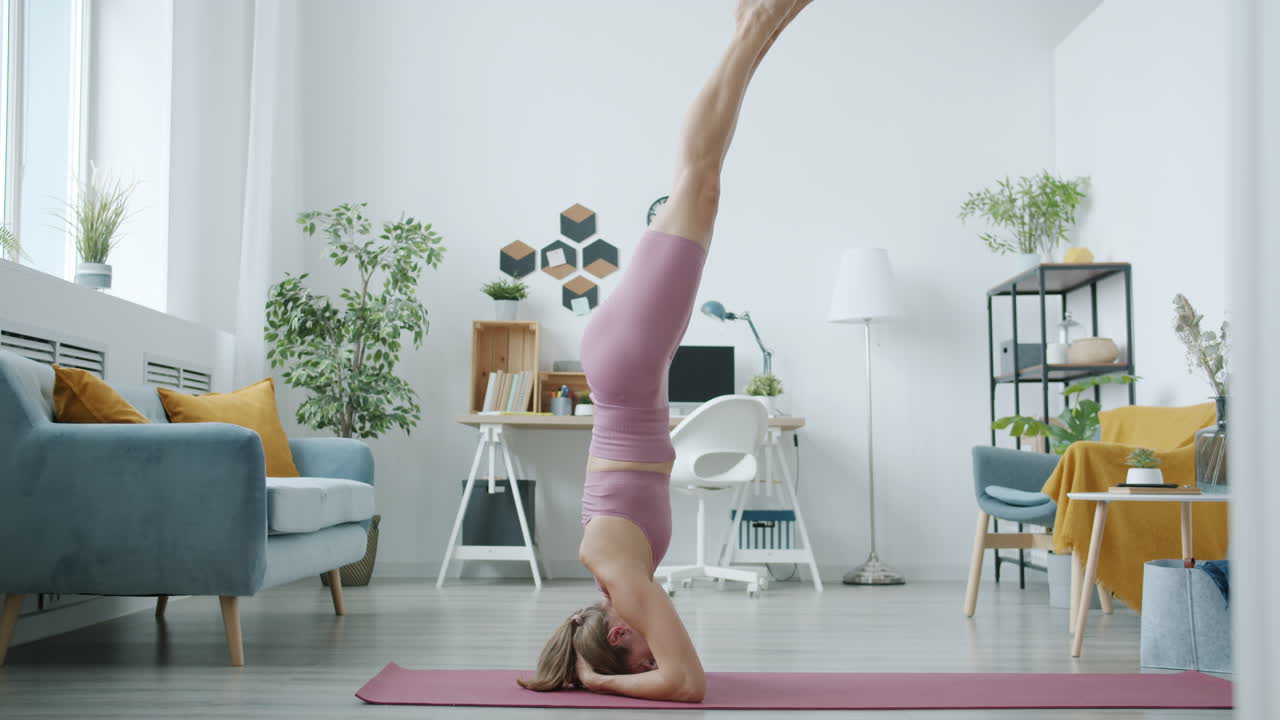 mujer realizando una postura de yoga de pie en la cabeza en casa