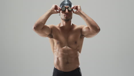 Athletic-young-biracial-athlete-swimmer-adjusts-his-swimming-goggles