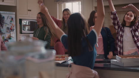 un grupo feliz de adolescentes bailando en la cocina comiendo pizza divirtiéndose celebrando juntos disfrutando de pasar el tiempo juntos en un fin de semana de fiesta