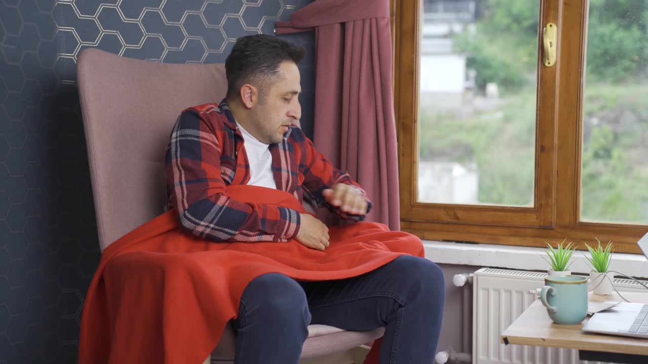 그 남자는 추워서 난방기를 만지고 있습니다.