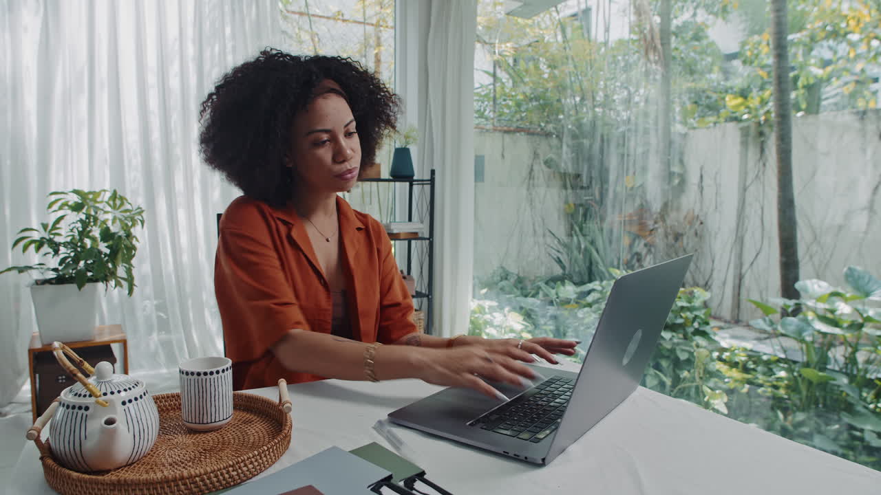 Remote Worker Filling Form on Laptop and Drinking Tea at Home Table