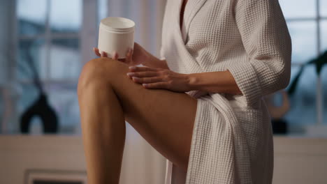 girl hand applying cream legs evening closeup. unknown woman moisturizing skin