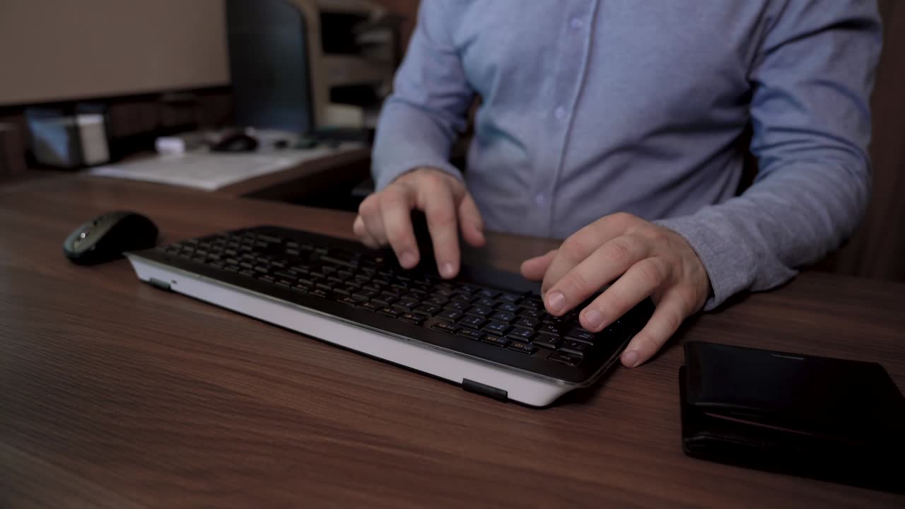un hombre se sienta en la mesa, escribe texto en el teclado y luego usa su tarjeta de crédito para pagar en línea.
