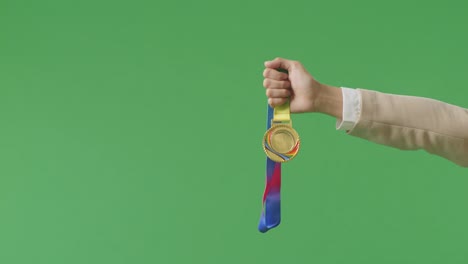cerca de la mano de la mujer de negocios sosteniendo una medalla de oro a su lado mostrando el premio ganador como el primer ganador en el fondo de la pantalla verde en el estudio