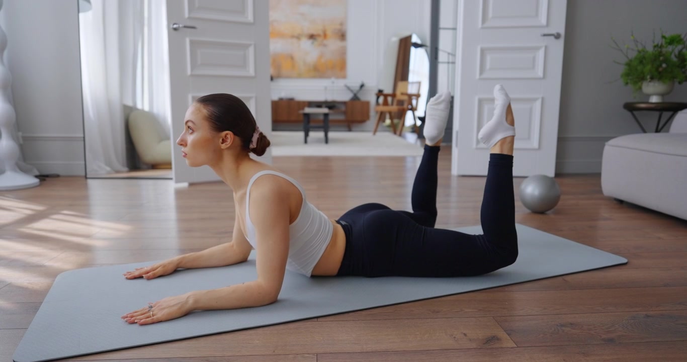 Young Woman Performing Leg Raises on Yoga Mat at Home