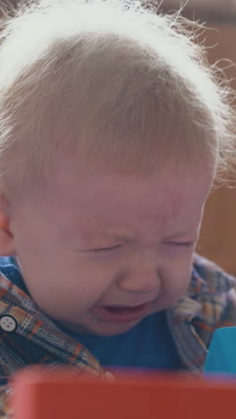 funny little boy upset of smashing color cubes tower on soft bed in light children extreme room close view