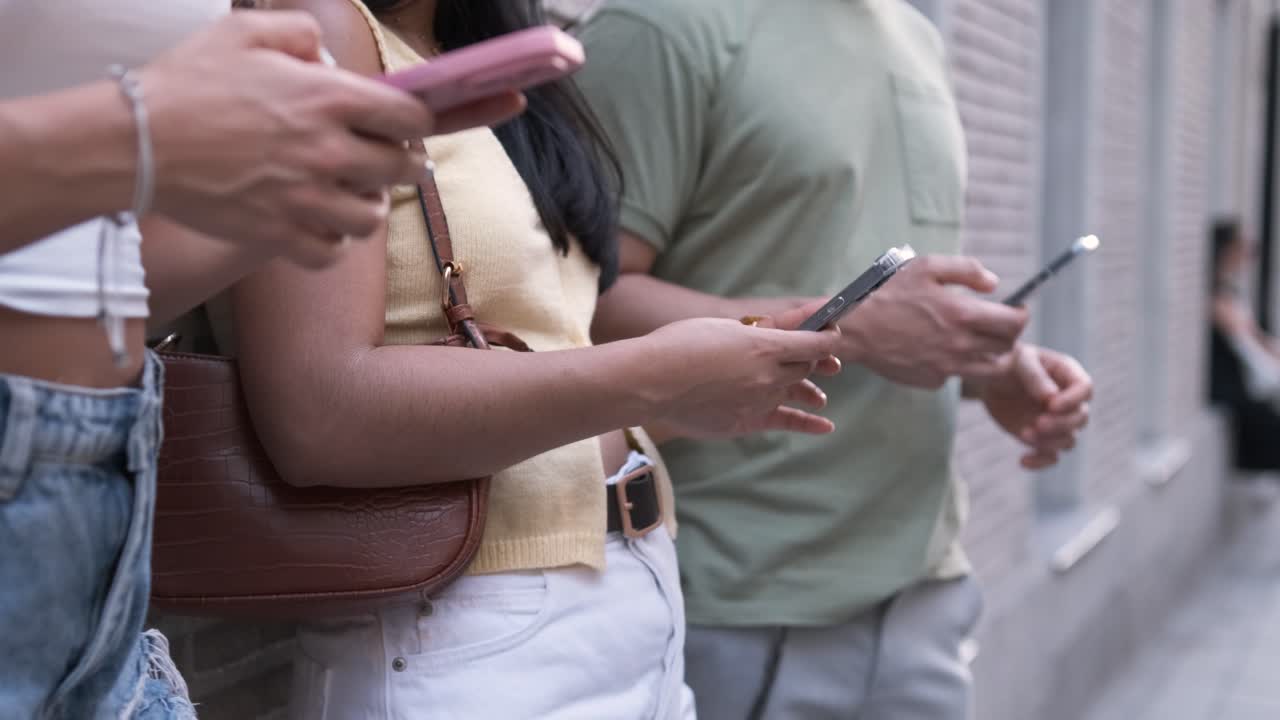 Anonymous friends using smartphones while standing in city