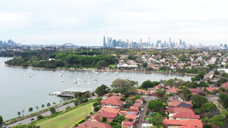 Aerial-drone-shot-flying-around-the-inner-west-bay-run-with-the-city-skyline-and-harbour-bridge-in-the-distance,-in-Sydney-Australia