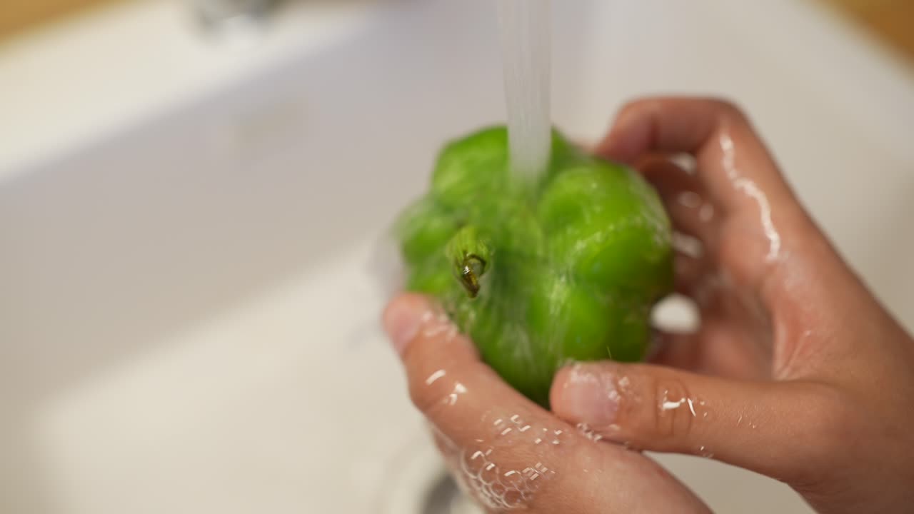 lavar un pimienta verde bajo agua corriente