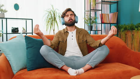 arabian man listening music, breathes deeply meditating with concentrated thoughts peaceful at home