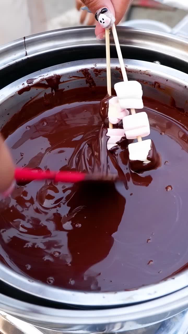 Intingere marshmallow nella fonduta di cioccolato fuso