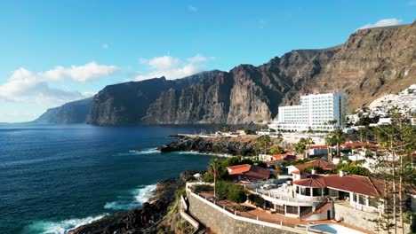 Drone-view-captures-the-scenic-Los-Gigantes-town-on-Tenerife,-showcasing-its-picturesque-coastal-charm-and-dramatic-cliffs-rising-majestically-against-the-Atlantic-backdrop