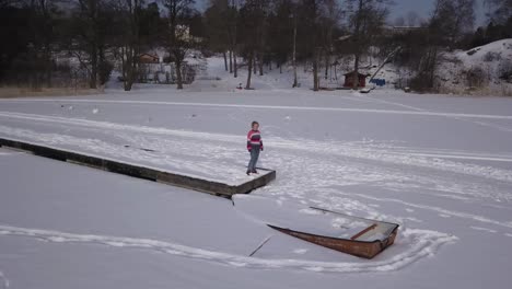 Low-angle-dolly-shot-rotating-around-lonely-girl-staring-over-the-infinite-vastness-of-a-frozen-lake