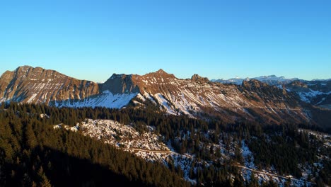 sunset light over mountains with partial snow patches
overflying pine forest, autumn colors