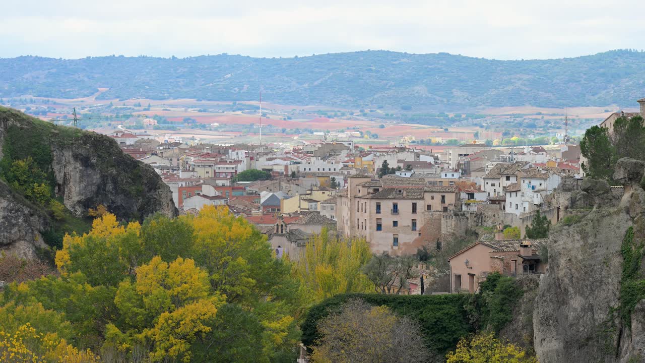 A scenic view of the historic UNESCO city, Cuenca, showing its unique cliffside architecture and surrounding landscape during a cool, overcast winter day in Spain.