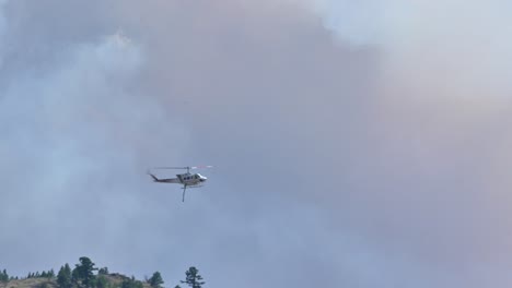 a firefighting helicopter navigates through the smoke of the ross moore lake wildfire