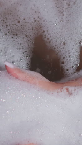 la mujer toma espuma esponjosa en la bañera de primer plano. la dama juguetona disfruta de un baño acogedor con espuma de jabón en el baño. la mujer descansa cuidando el cuerpo y la piel en casa