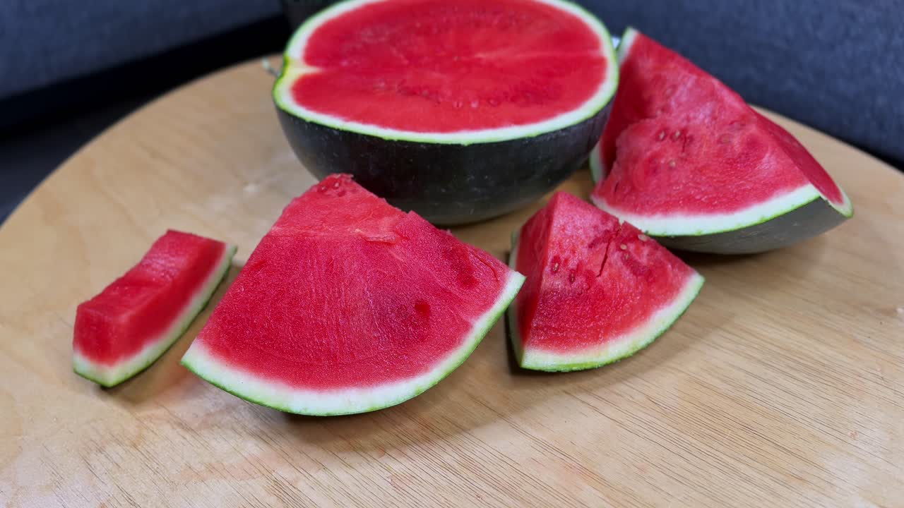 Close-up of hands holding juicy watermelon slices on a wooden table with more fruit in the background, perfect for food, summer, health, lifestyle, and nutrition projects