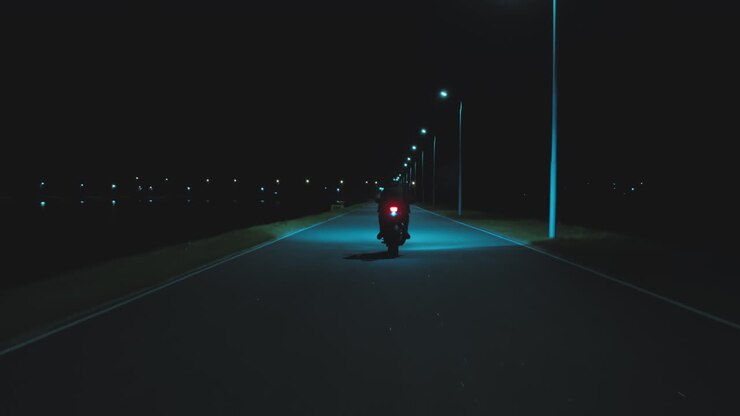 A man moving away on a sports motorcycle into the distance against the backdrop of a night city