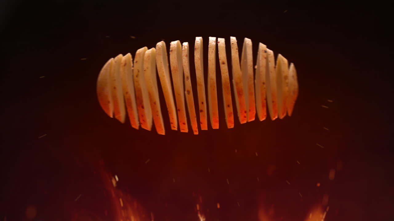 horneando papas fritas en un fuego abierto, la patata salta y se rompe en rebanadas en cámara lenta