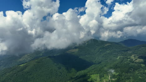 flying trough white fluffy clouds above green mountain peaks